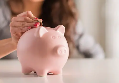 A woman putting a coin in a piggy bank
