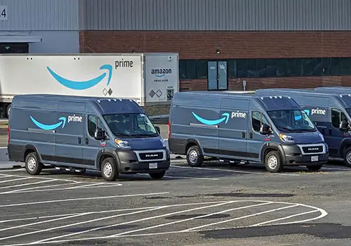 Amazon vans and trailer outside an Amazon warehouse