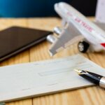 A model airplane on a desk next to a checkbook and pen.