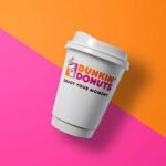 A Dunkin' Donuts coffee cup against their famous pink and orange background.