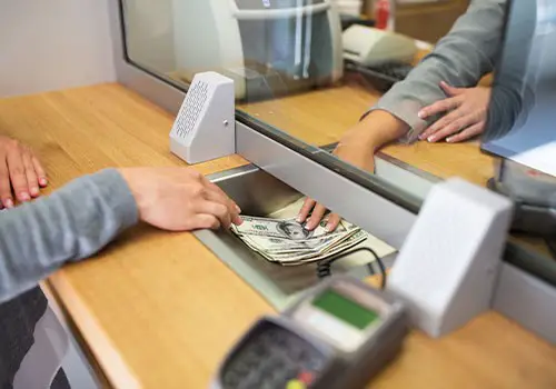 A bank teller handing cash over to a customer.