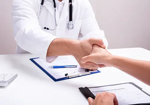 Male doctor shaking hands with a female nurse in a clinic.